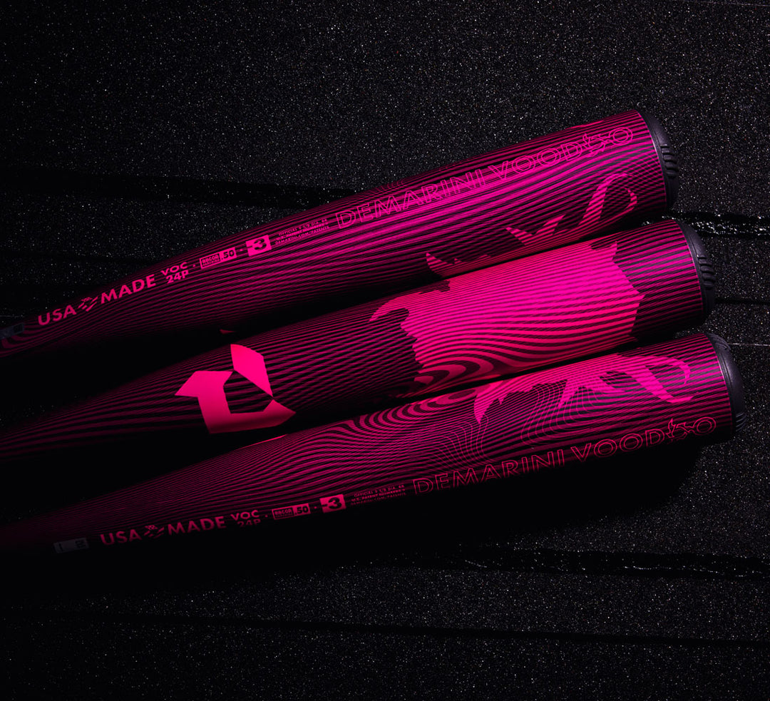 Three 2024 DeMarini Voodoo One Neon Pink (-3) BBCOR Baseball Bats (WBD2557010) rest side by side on a textured black surface, highlighting bold graphics, DeMarini logos, and the signature X14 Alloy Barrel.