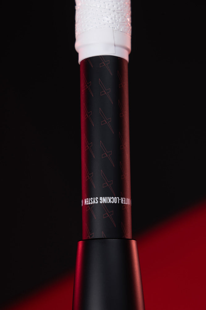 Close-up of the Marucci 2025 CATX2 Composite (-10) USA Baseball Bat's black and white grip with Anti-Vibration Technology and OUTER-LOCKING SYSTEM text, set against a vivid black and red background.