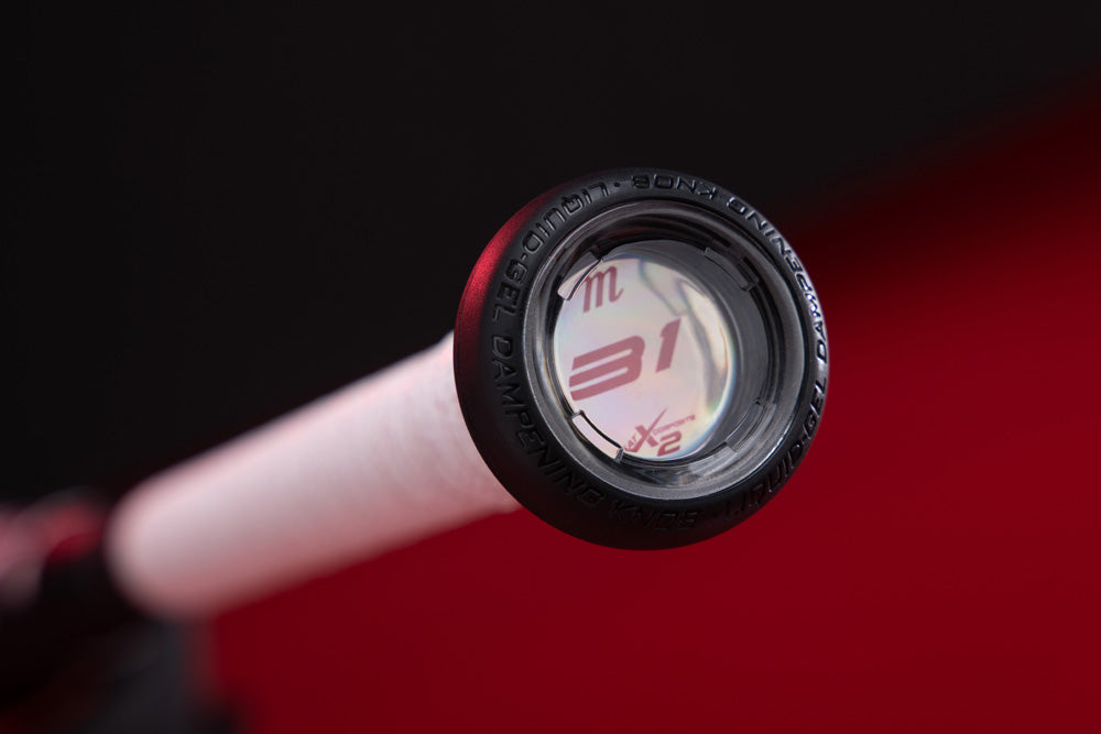 Close-up of the Marucci CATX2 Composite (-10) USA Baseball Bat’s knob featuring a white grip and an end cap marked 31/32. The black and red background showcases the advanced anti-vibration technology of this 2025 MSBCCPX210USA model.