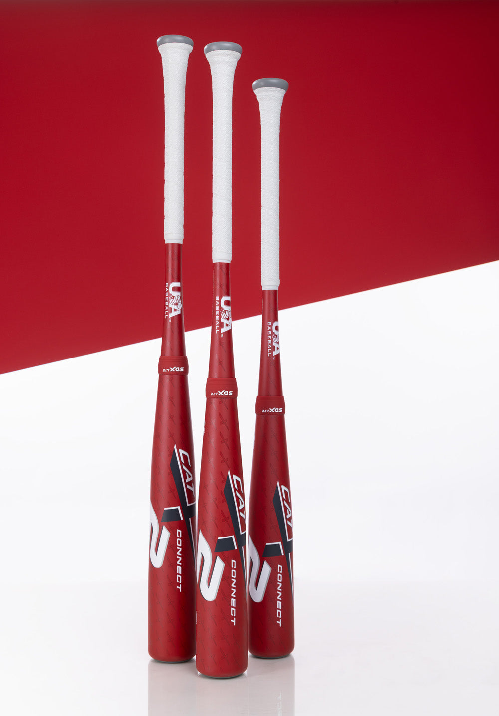 Three Marucci 2025 CATX2 Connect (-8) USA Baseball Bats (MSBCCX28USA), with white handles and red-and-white color scheme, stand upright side by side against a matching geometric background.