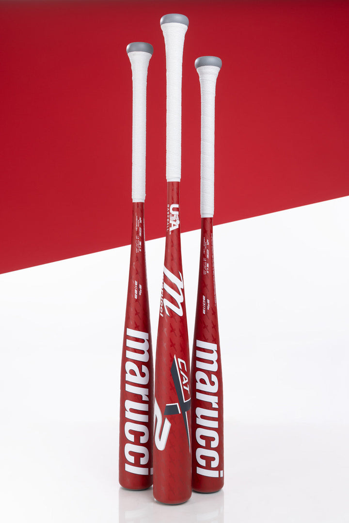 Three Marucci CATX2 (-8) 2 5/8" USA Baseball Bats stand upright with white grips against a red-and-white geometric background, showing off visible logos and the advanced one-piece alloy construction of the 2025 MSBCX28USA model.