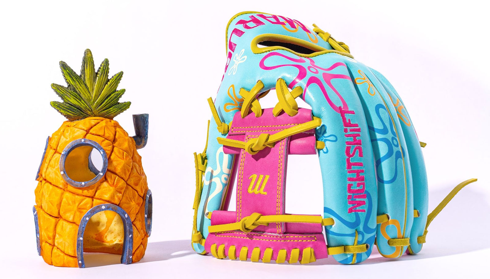 A baseball glove with colorful blue, yellow, and pink designs sits next to a model of a pineapple-shaped house with windows and green leaves on top, inspired by SpongeBob SquarePants.