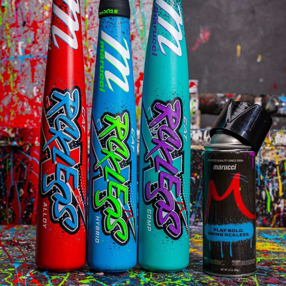 Three vibrant Marucci baseball bats, including the 2026 CAT X RCKLESS Hybrid (-11) USA Bat (MSBCRH11USA), stand upright beside a can of Marucci spray paint against a splattered, paint-splashed backdrop.