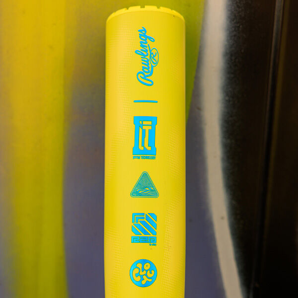 A close-up of the 2026 Rawlings Clout AI (-3) BBCOR Baseball Bat (RBB6C3) in bright yellow, featuring blue icons and the Rawlings logo, set against a background with vertical yellow, brown, and black streaks.