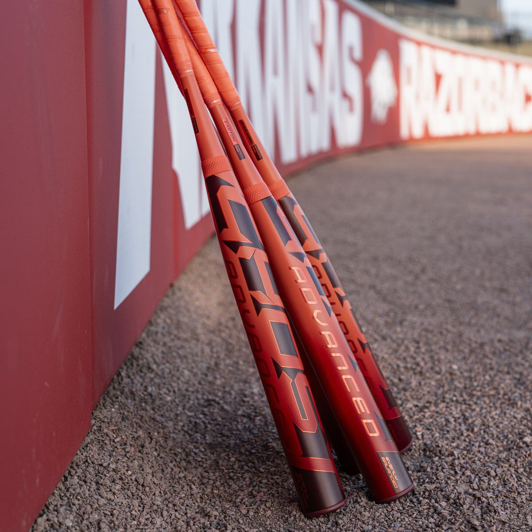 A group of baseball bats, including the 2026 Easton Ghost Advanced (-8) Fastpitch Softball Bat (EFP6GHAD8) by Easton, leaning against a wall.