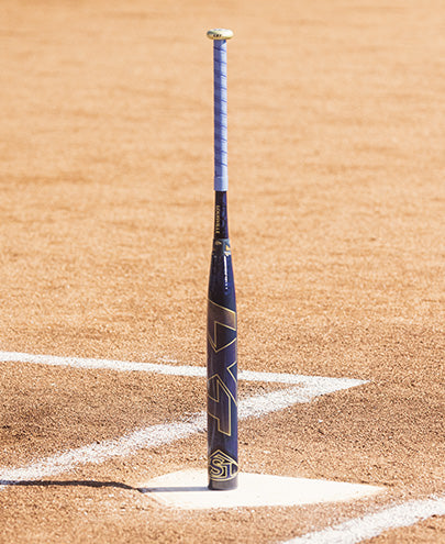 A 2025 Louisville Slugger LXT (-9) Fastpitch Softball Bat (WBL2995010) rests on the dirt field, ready for the next big swing.