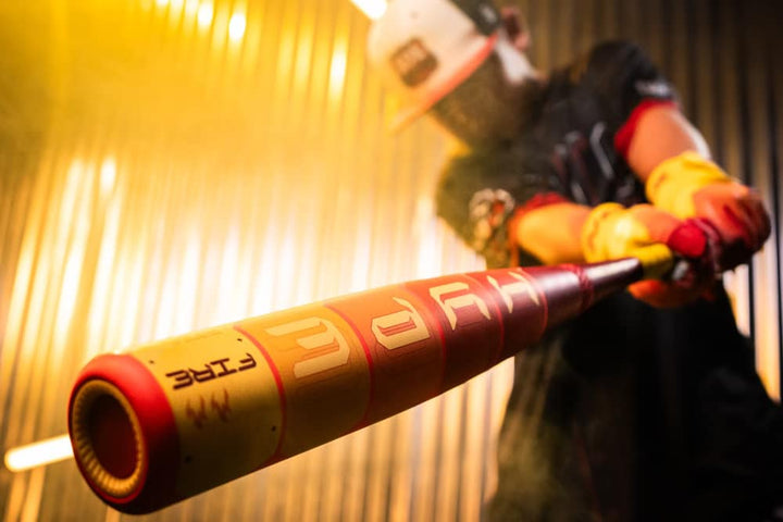 A player in a helmet and gloves swings the 2025 Easton Hype Fire (-5) 2 5/8" USA Baseball Bat (EUS5HYP5) by Easton, its vivid yellow-red barrel with advanced 3D Ropecoil composite pops against a blurred, dynamic background.