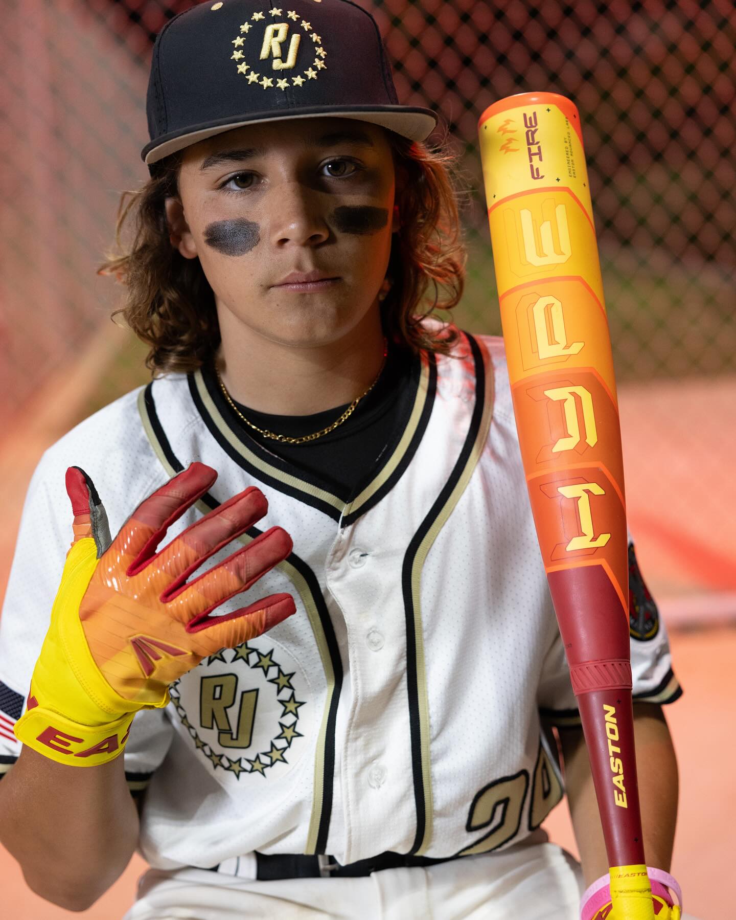 A boy holding the 2025 Easton Hype Fire JBB (-10) 2 3/4" USSSA Baseball Bat (EJB5HYP10), featuring advanced Thermo-Composite technology.