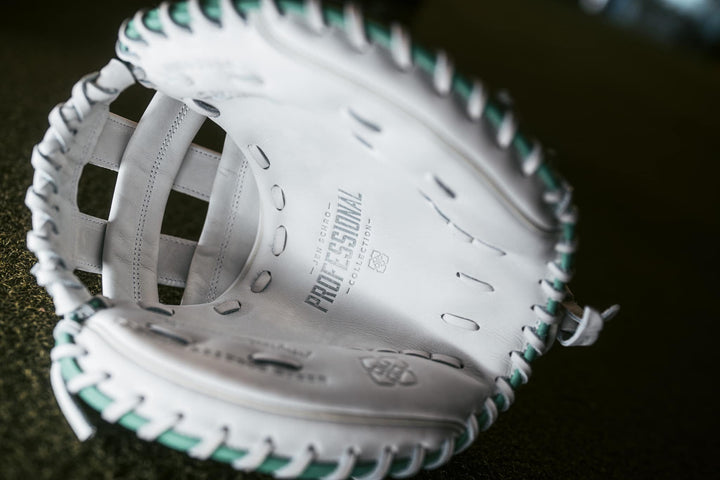 A close-up of the Easton Jen Schro "The Rudi" 34" Fastpitch Catcher's Mitt (RUDI-2024), crafted from premium USA steerhide leather in white with green stitching, shows the palm area embossed with "Professional Collection.