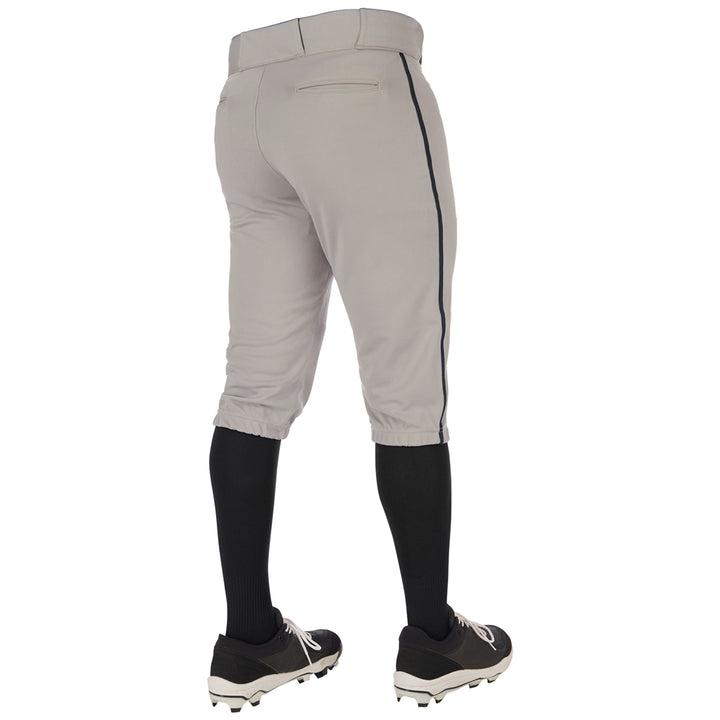 A person is seen from the back wearing Champro Sports Triple Crown 2.0 Youth Knicker Baseball Pants with black side piping (BP70Y), paired with black knee-high socks and black cleats, against a plain white background.