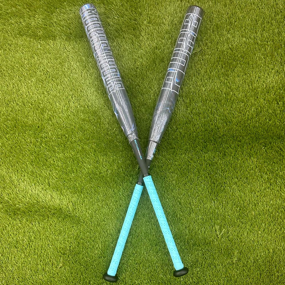 A pair of composite bats, including the Pure Sports 2025 Storm Shadow 13″ Balanced USA Slowpitch Softball Bat (5147M91B), rests on the grass.