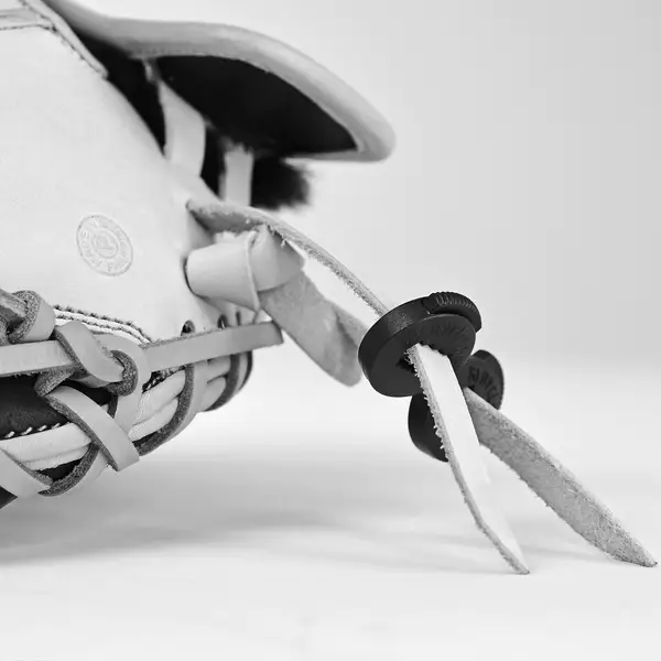 Close-up of a baseball glove’s laces with two black plastic lace locks securing the leather strips, shown against a plain, light background.