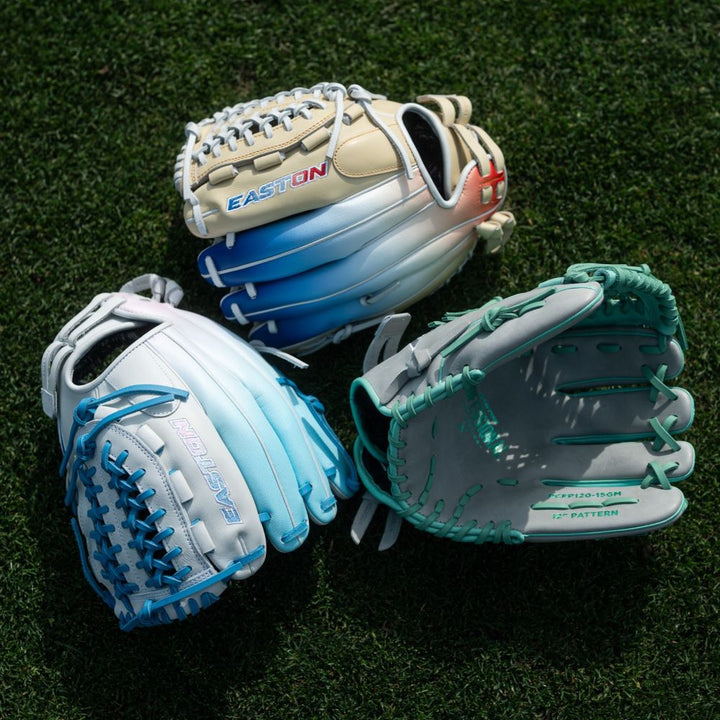 A group of Easton Professional Collection Color Splash 12.5" Fastpitch Softball Gloves (PCFP125-3WCBP), crafted from premium USA steerhide, rests on the grass.