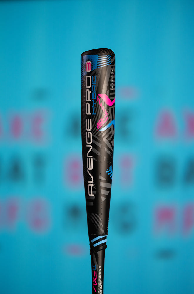A close-up of the 2024 AXE Avenge Pro 3 Hybrid (-8) 2 5/8" USA Baseball Bat (L174M), in black and blue with pink and white accents, is displayed vertically against a blurred blue background.