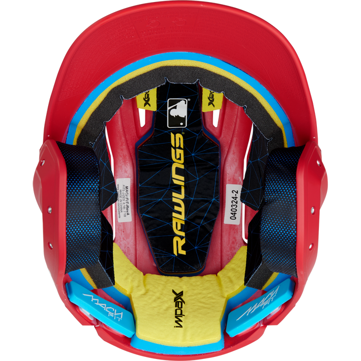 Top-down view of a red Rawlings Mach Fit Matte Batting Helmet (MACHFIT) with black, yellow, and blue IMPAX foam interior padding, white labels, and the MLB logo visible inside. Brand: Rawlings.