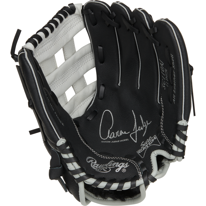 The Rawlings Sure Catch 11" Aaron Judge Youth Baseball Glove (SC110AJ) features a black and white design with white laces and Aaron Judge's signature on the palm.