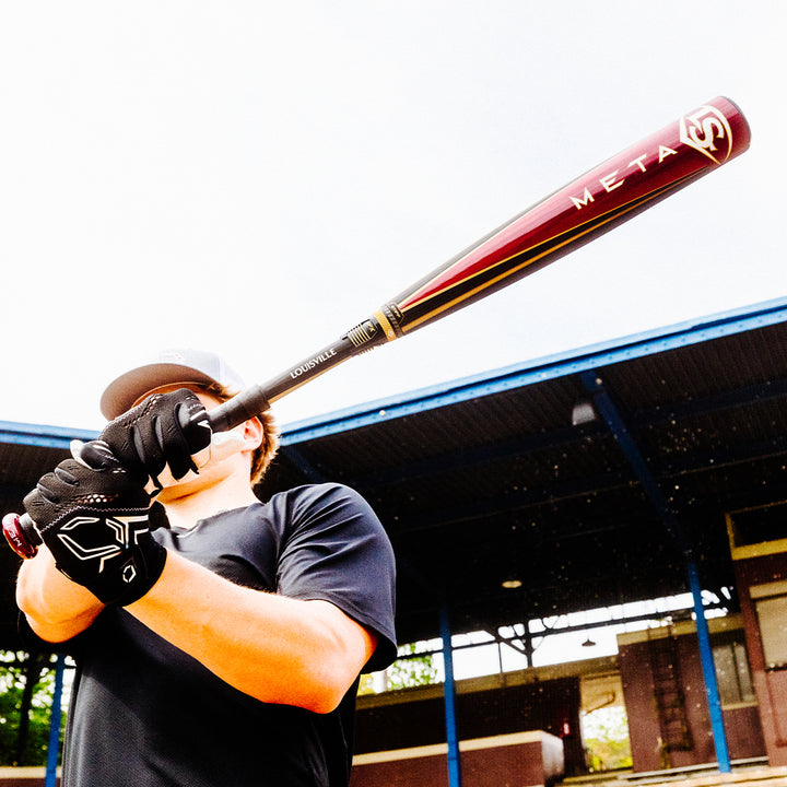 A man holding a two-piece composite baseball bat, like the 2025 Louisville Slugger Meta (-3) BBCOR Baseball Bat: WBL2966010 (USED) from Louisville Slugger.