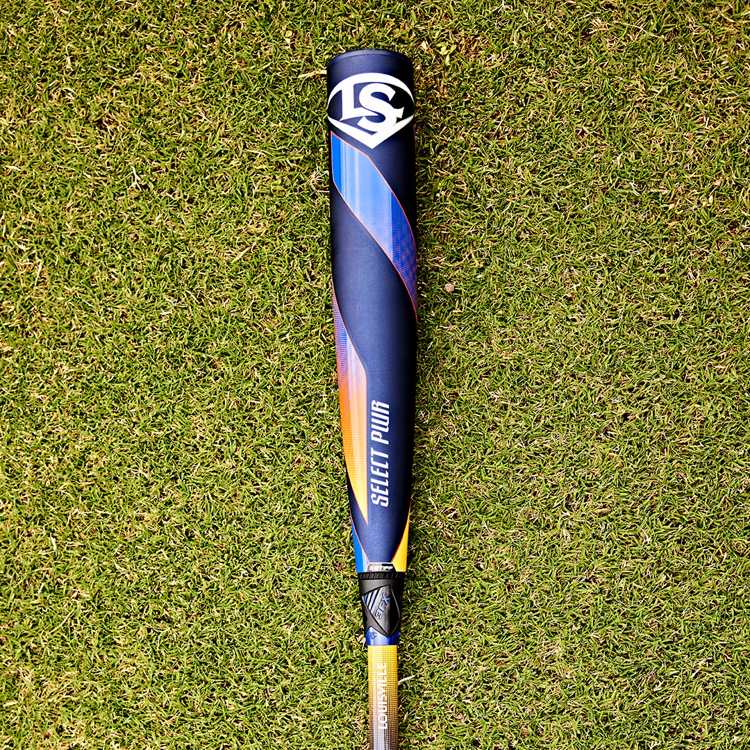 A 2025 Louisville Slugger Select PWR (-3) BBCOR Baseball Bat (WBL2967010) sits on the grass, its EXD Premium Alloy Barrel shining in the sunlight.