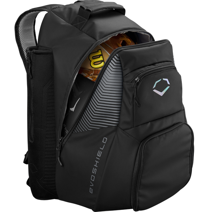 The EvoShield Tone Set Backpack (WB57304) is a black, water-resistant baseball gear bag with multiple compartments, bat sleeves, and a subtle EvoShield logo on the front pocket. The partially unzipped bag reveals a glove and bat inside.