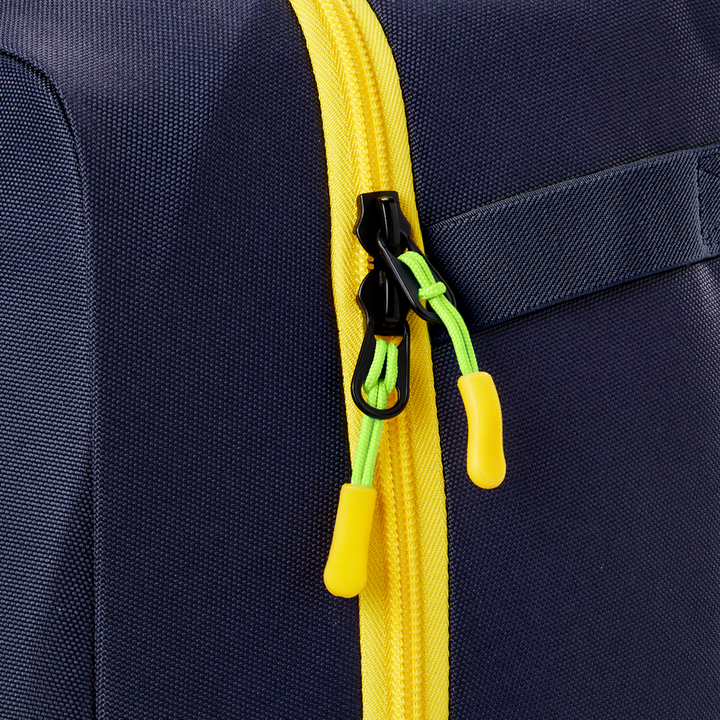 Close-up of the Louisville Slugger Savannah Bananas Powerized Stick Pack Backpack (WB57636), a navy blue youth baseball bag featuring a yellow zipper, green zipper pulls with yellow tabs, and a partially visible fabric handle on the right.