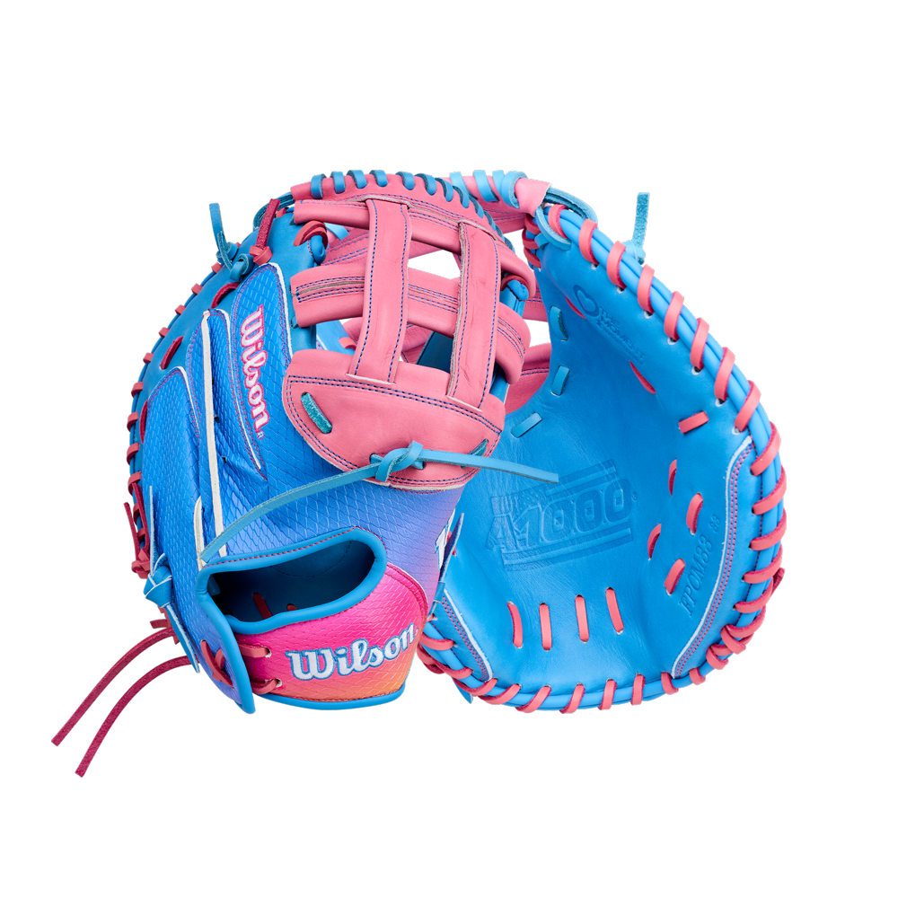 Two vibrant Wilson A1000 FPCM33 MOMENTUM 33″ Fastpitch catcher’s mitts, showcasing bold blue and pink hues with bright laces and vivid stitching, are displayed against a white background. The image highlights both the interior and exterior of each glove, which feature a 33” circumference and are expertly crafted from durable Full Grain leather.