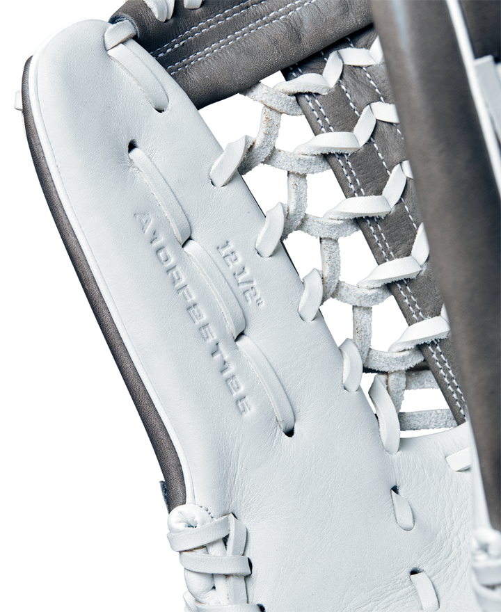 Close-up of the Wilson A1000 T125 12.5" Fastpitch Glove, crafted from full grain leather with detailed lacing and visible embossed text. The glove features white and gray colors, with stitching and leather details clearly shown.