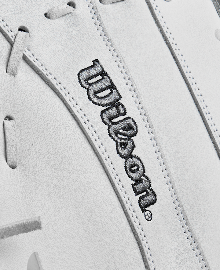 Close-up of the Wilson A1000 1620 12.5" Fastpitch First Base Mitt's white full-grain leather surface with gray laces and Wilson embroidered in black, highlighting its premium quality.