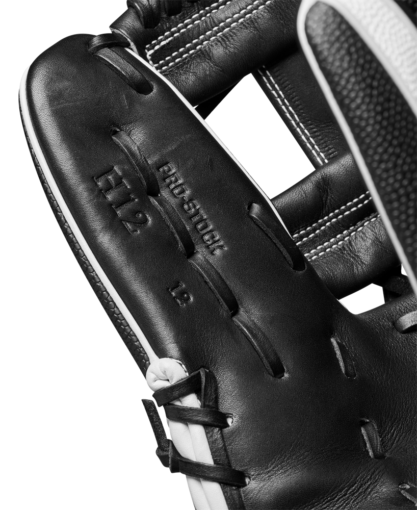 Close-up of a Wilson A2000 H12SS 12" Fastpitch Glove (WBW10262412) in black leather, featuring visible stitching, PRO STOCK H12 12 stamping on the palm, and premium SuperSkin material. Part of a baseball is seen at the edge.