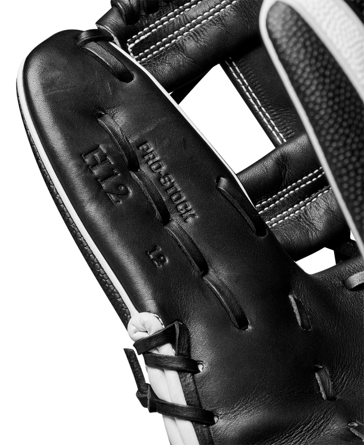 Close-up of a Wilson A2000 H12SS 12" Fastpitch Glove (WBW10262412) in black leather, featuring visible stitching, PRO STOCK H12 12 stamping on the palm, and premium SuperSkin material. Part of a baseball is seen at the edge.
