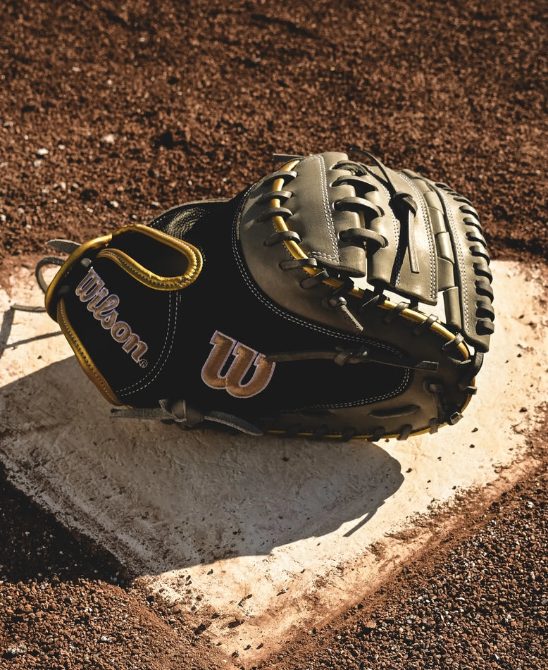 A Wilson A2000 FPCM23 34" Fastpitch Catcher's Mitt (WBW10274434) sits on home plate, its Pro Stock leather gleaming in the sunlight of the baseball field.