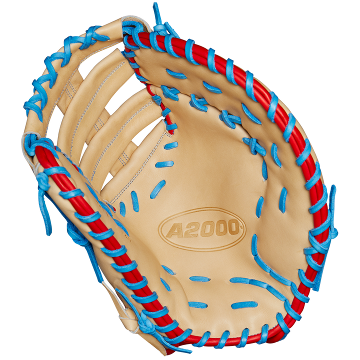 The Wilson A2000 1677 12.5" First Base Mitt (Spring 2025, WBW102753125) features tan Pro Stock leather, blue and red laces, detailed stitching, an open web, and the A2000 logo in the palm.