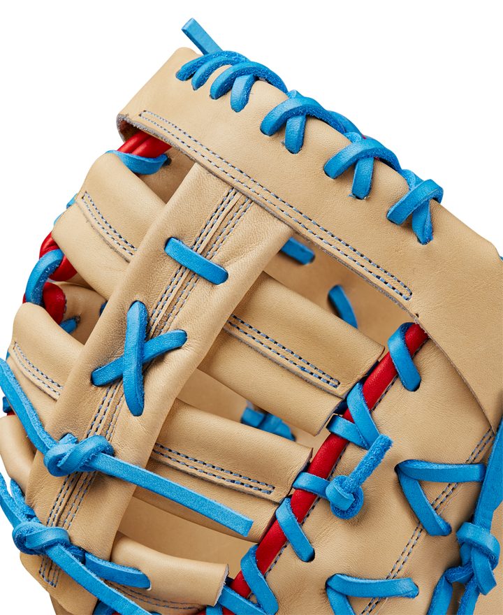 Close-up of the Wilson A2000 1677 12.5" First Base Mitt, featuring tan Pro Stock leather, bright blue laces, red accents, and detailed stitching with a woven web design. Model: WBW102753125, SPRING 2025.