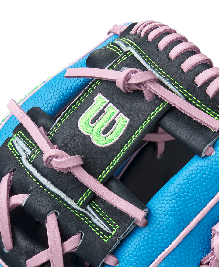 Close-up of the Wilson A2000 1786SS 11.5" Baseball Glove (GOTM March 2025) in blue with pink laces, black Pro Stock leather, green stitching, and a green embroidered W logo.