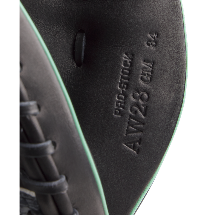 Close-up of black leather and light green trim on the Wilson A2000 AW28 34" Austin Wells Gameday Catcher's Mitt, FALL 2025 (WBW10349434), showing embossed "PRO-STOCK," "AW28 CM 34," and other markings inside the mitt.