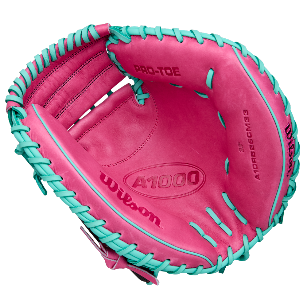 A Wilson A1000 CM33 33" Baseball Catcher's Mitt (WBW10396633) in pink with teal laces, seen from above to reveal the palm and interior branding. Crafted from full grain leather by Wilson.