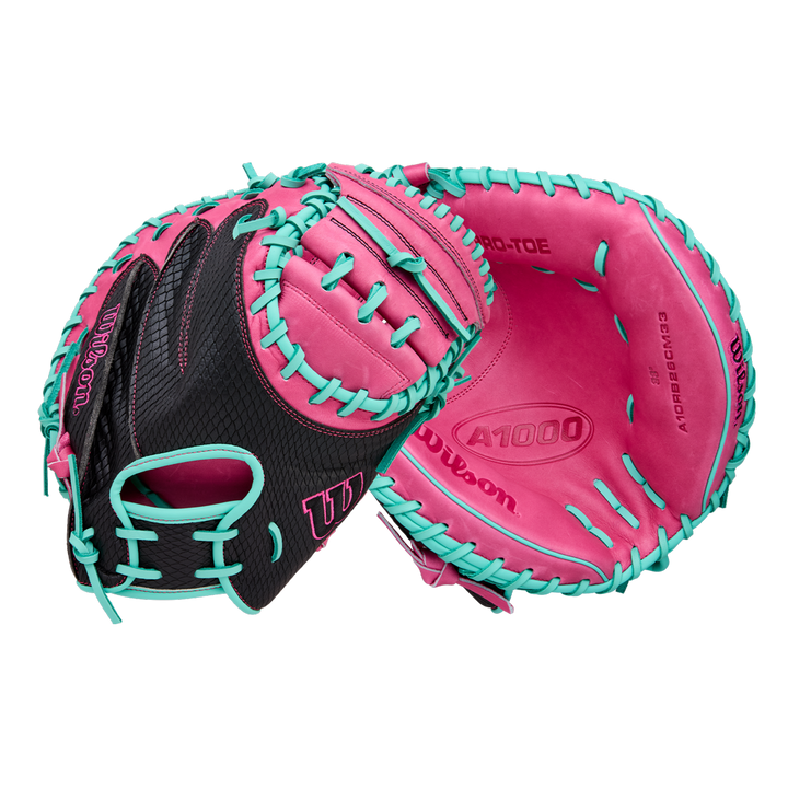 The Wilson A1000 CM33 33" Baseball Catcher's Mitt (WBW10396633) by Wilson features a black design with bright pink palm and teal blue lacing, crafted from full grain leather—ideal for youth catchers. Shown front and back on white background.