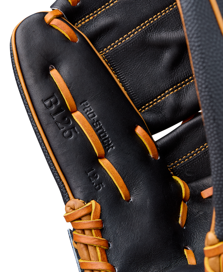 Close-up of the Wilson A2000 B125SS 12.5" Baseball Glove (WBW104119125), featuring black leather with yellow-orange laces, visible stitching, SuperSkin material, and embossed B125 and PRO STOCK on the palm.