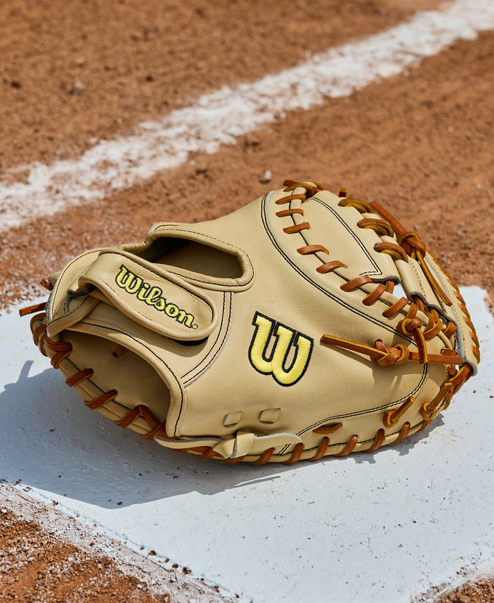 A Wilson A2000 PF33 33" Baseball Catcher's Mitt (WBW10412733) by Wilson, made with Pro Stock Leather and brown laces, rests on a white chalk baseline of a dirt baseball field.