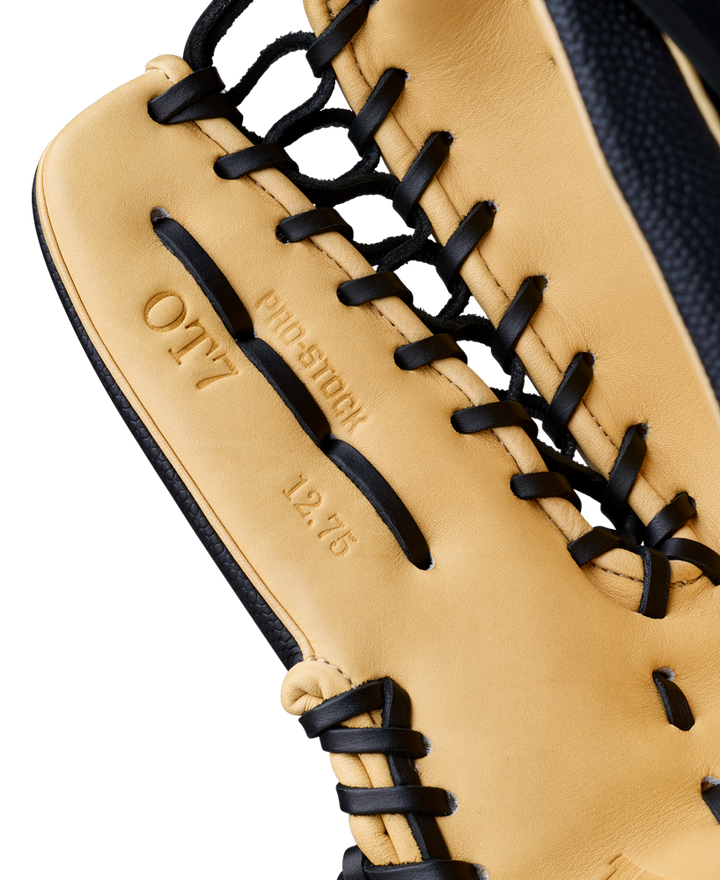 A close-up of a tan and black Wilson A2000 OT7SS 12.75" Baseball Glove, highlighting its detailed stitching, black laces, and embossed text—PRO STOCK, OT7, and 12.75—on the leather.