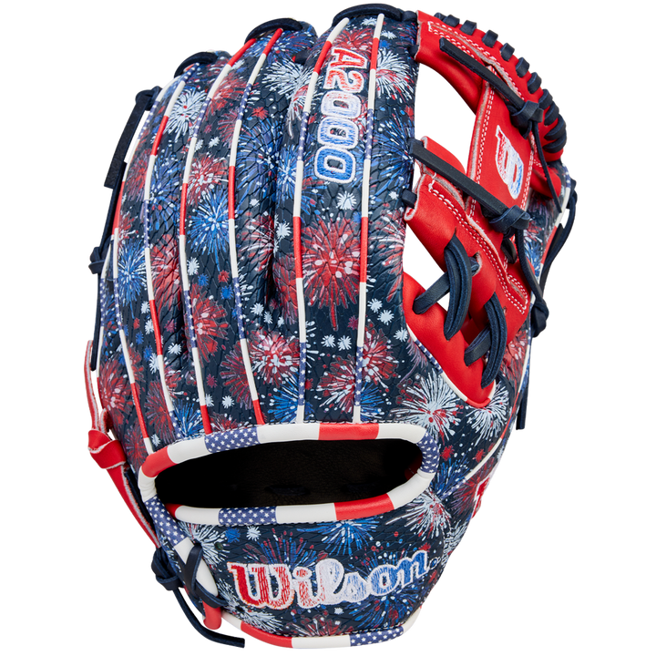 The Wilson A2000 1975SS 11.75" Baseball Glove (GOTM July 2025) features Pro Stock leather and a red, white, and blue fireworks design with stars, stripes, and the Wilson logo on the wrist.