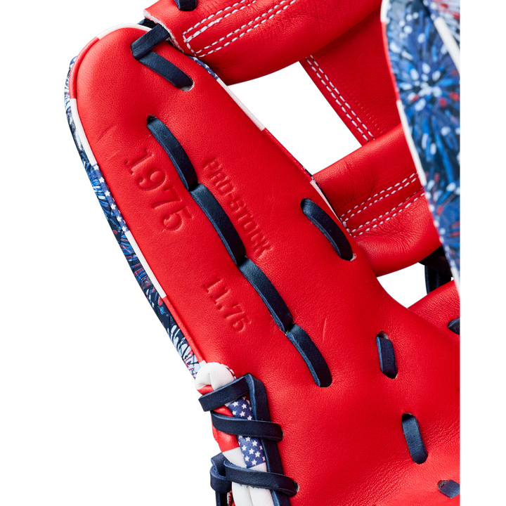 Close-up of the Wilson A2000 1975SS 11.75" Baseball Glove (GOTM July 2025) featuring red Pro Stock leather, navy blue and white laces, embossed "PROEDITION," "1975," and "11.75" on the inner palm, with patterned blue edges.