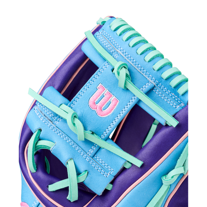 Close-up of the Wilson A2K 1720 11.5" GOTM October 2025 Baseball Glove, showcasing blue, purple, and teal Pro Stock Select leather with green laces and a pink-embroidered W logo on a blue patch.