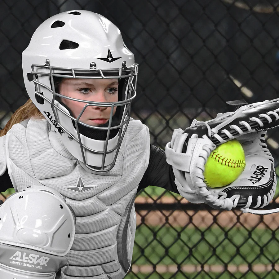 A woman in a baseball uniform holds a softball and wears the All Star Heiress 32.5" Fastpitch Catcher's Mitt (CMW-H-Y) by All Star, ready to play.