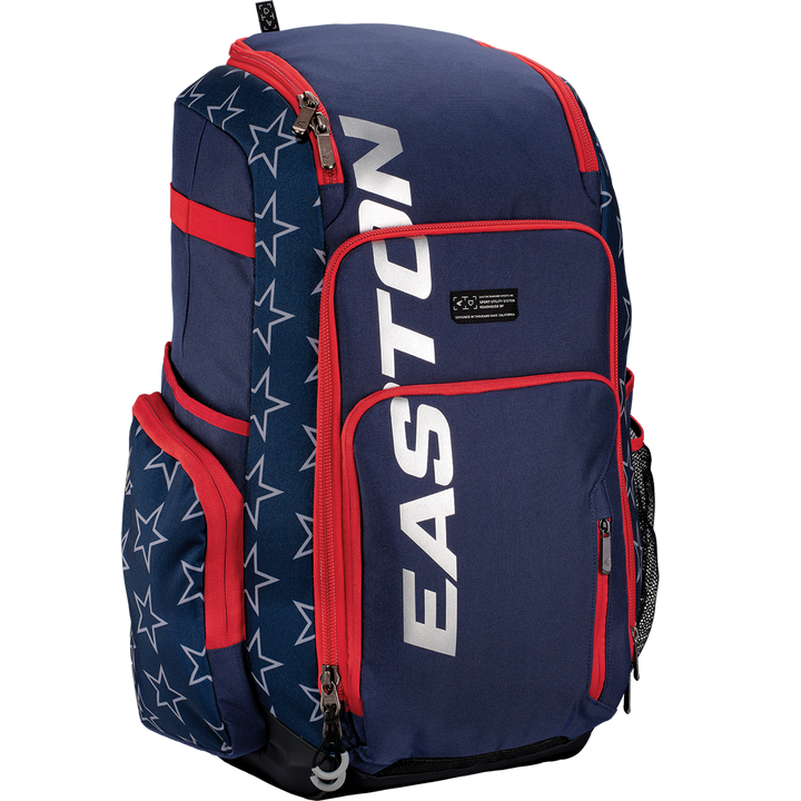 The Easton Roadhouse Backpack (EBA004) by Easton features navy blue and red colors, white star patterns, "EASTON" in silver on the front pocket, plus multiple compartments and side pockets for baseball or softball gear.