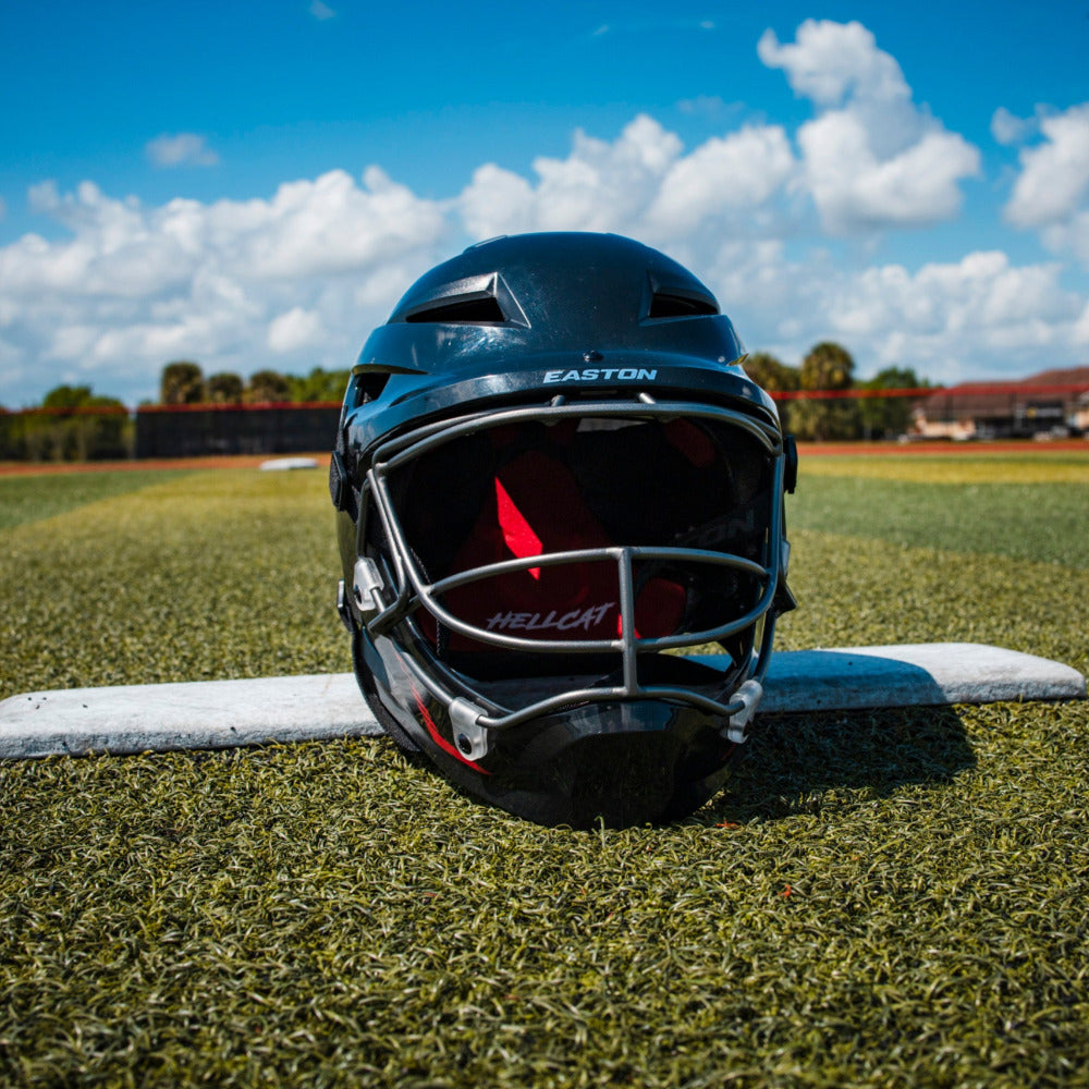 The Easton Hellcat Slowpitch Fielding Helmet (EHCATH) by Easton rests on the field, showcasing essential protective gear ready for action.