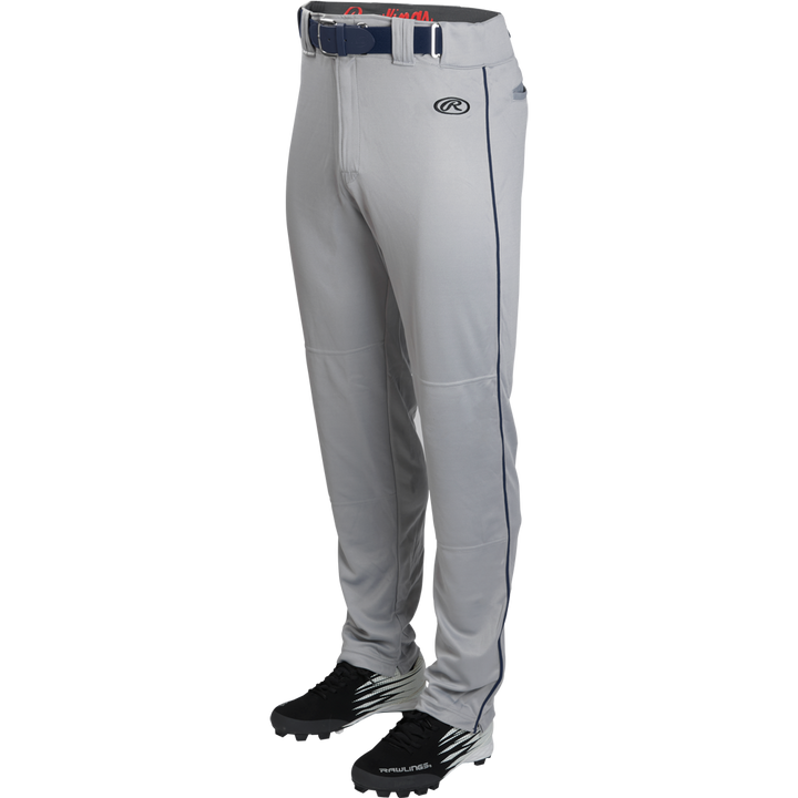 A pair of Rawlings Youth Launch Semi-Relaxed Baseball Pants with navy piping and waistband, shown with black cleats on a white background.