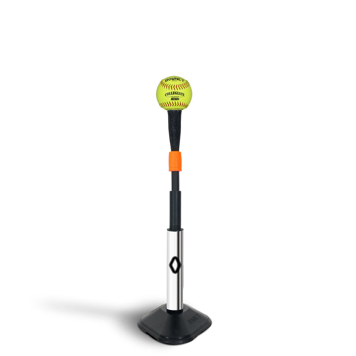 A yellow softball sits on the Bownet ProMag Batting Tee (BN-PROMAG TEE) by Bownet, featuring a black and silver adjustable stem with an orange ring on a black base, all against a white background.