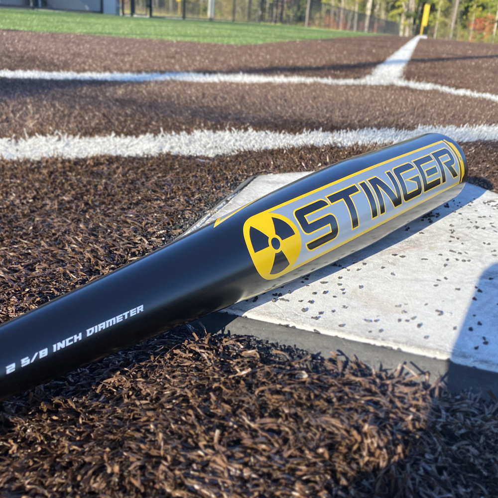 The 2022 Stinger NUKE 2 (-3) BBCOR Baseball Bat by Stinger Sports, featuring Power Loaded Barrel Technology, rests on the field, ready for the next home run.