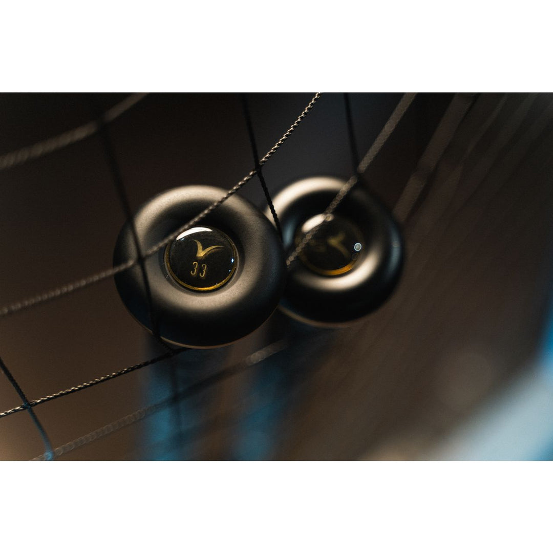 Two black hockey pucks rest on netted strings, one marked with gold 33 in soft light—echoing the poised power of the 2022 Victus Vandal 2 (-8) USSSA Baseball Bat: VSBV2X8 from Victus, ready for its next big hit.