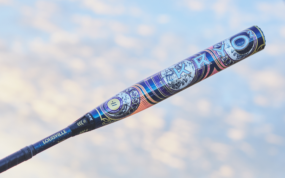 The 2027 Louisville Slugger Kryo2 Empress (-8) Fastpitch Softball Bat: WL2700601 features bold, intricate graphics wrapping the barrel, shown against a soft, cloudy sky backdrop.